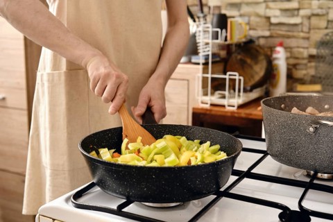 Cooking chopped bell peppers in a modern kitchen with natural light streaming through the window