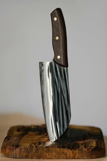 Serbian kitchen knife stuck in a rustic wooden block. The knife features a sleek, shiny blade with