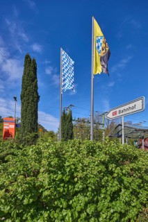Bad Reichenhall-Kirchberg railway station, hedge, trees, flagpoles, Bavarian flag, Bad Reichenhall