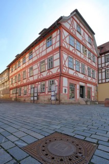 Red Luther House and square manhole cover with town coat of arms, cobblestones, view from below,