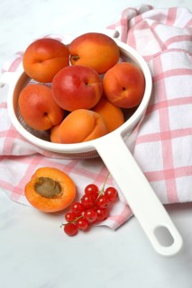 Apricots in a colander and redcurrants