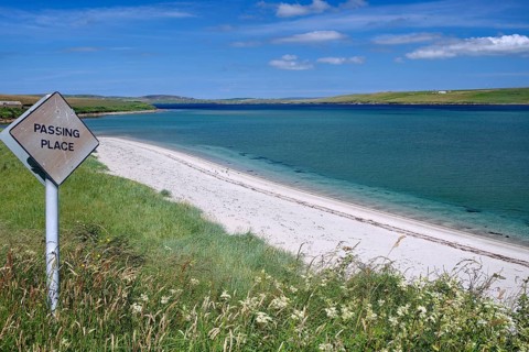 Coastal road with a warning sign, situated on a white sandy beach, Hoy, Orkney Islands, Scotland,