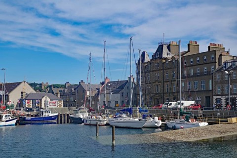 Coastal harbour with sailing boats and historic buildings under a bright blue sky, Kirkwall, Orkney