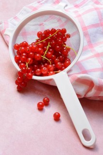 Redcurrants in kitchen sieve, Ribes rubrum