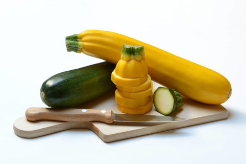 Green and yellow courgettes on a wooden board, Cucurbita pepo