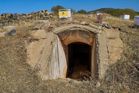 Lost Place, concrete bunker entrance in dry landscape under blue sky with vegetation, Italian air