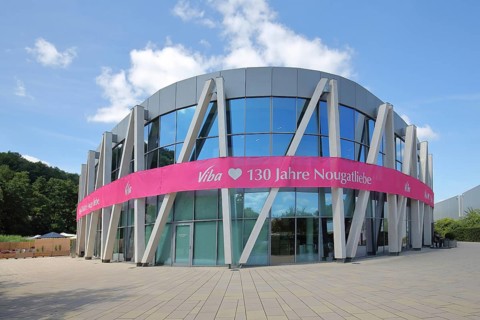 Modern round building with glass window and pink banner with inscription, anniversary 130 years of