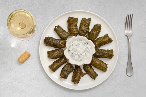 Dolma is being prepared at home, featuring grape leaves stuffed with rice, lamb meat and herbs,