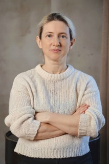 A woman poses confidently with her arms crossed, dressed in a soft, knitted sweater