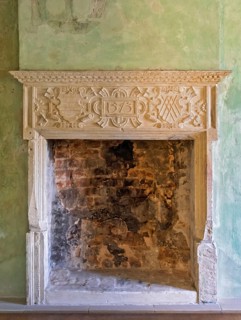 Artfully carved stone fireplace in green antique surroundings with exposed bricks, Lüdinghausen