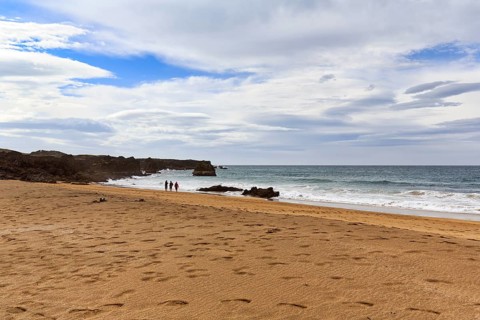 Skarðsvík Beach, walkers in a bay, golden sandy beach and rocky coast, coastal landscape,