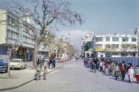 Primary school children walking hand in hand along city centre commercial street, Macau, Asia 1964