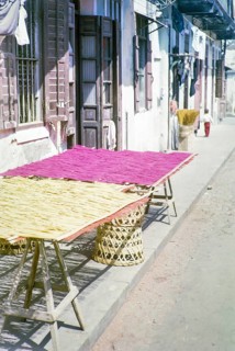 Woven bamboo mats laid out on trestle table outside traditional building, Macau, Asia 1964