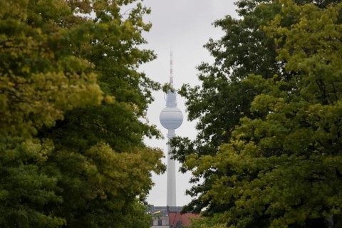 Berlin television tower with cloud-covered top between trees in the government district in Berlin,