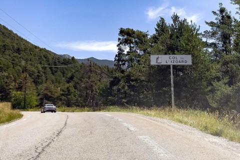On the right tourist sign at the beginning of the mountain pass road to the Alpine pass with the