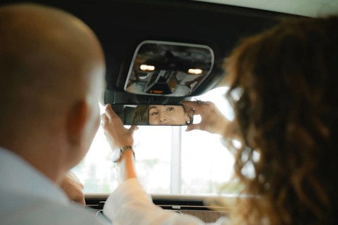 The view from the rear seat of the car is a couple of sitting in front. A woman sets up a rear view