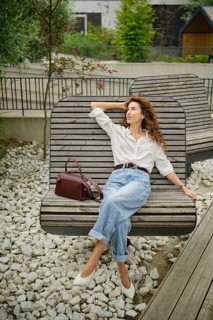 A woman enjoys her time on a stylish bench in a contemporary outdoor area filled with greenery. She