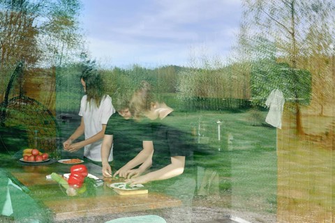 The view through the window to the kitchen, where the family is preparing a light snack. The glass
