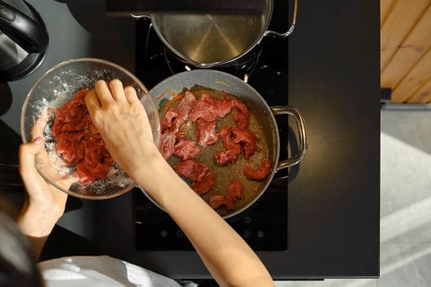Slicing lean beef into strips and adding it to a hot pan, this skilled cook is preparing a healthy