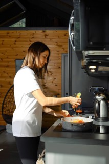 A woman prepares a healthy vegetarian dish in a charming kitchen. Bright vegetables are being added