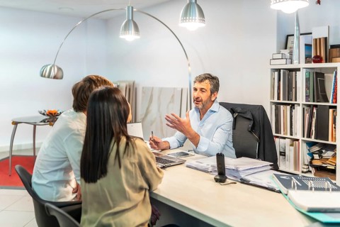 Architect discussing home renovation project with couple in furniture and tile showroom, providing
