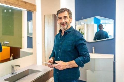 Smiling mature male architect using a digital tablet while choosing bathroom fixtures in a home