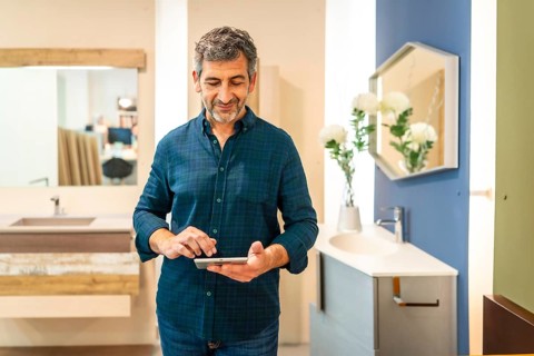 Mature architect using digital tablet choosing bathroom fixtures in home improvement store, smiling