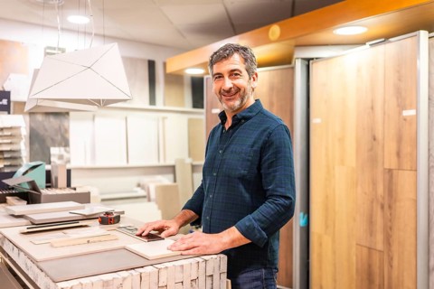 Smiling architect choosing material samples in a home improvement store, he is touching ceramic and