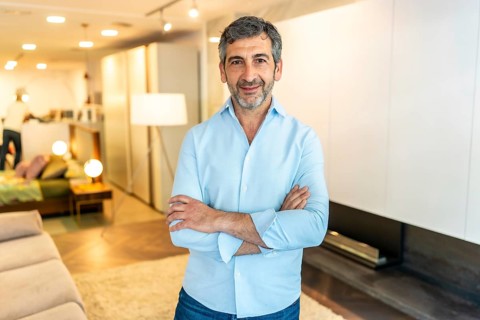Smiling salesperson with crossed arms, exuding confidence while standing in a modern furniture