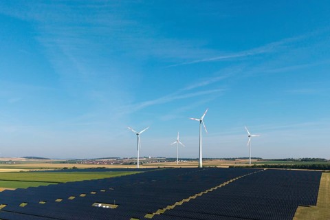 Fields full of solar panels with several wind turbines under a cloudless sky, near Kitzingen, Lower