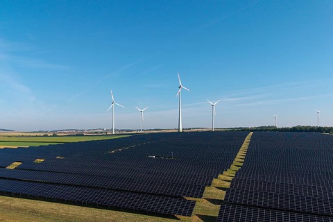 Solar panels and wind turbines on a wide field under a clear sky, near Kitzingen, Lower Franconia,