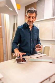 Architect using a digital tablet and choosing tiles in a home improvement store, holding a