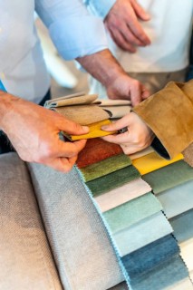 Customers and sales assistant choosing upholstery fabric from a wide variety of colors and textures