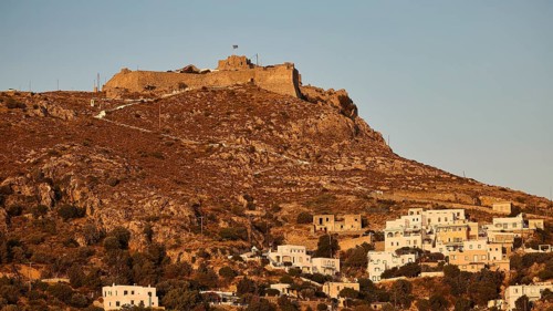 Settlement with castle on a hill in the warm light of the evening sun, surrounded by vegetation,