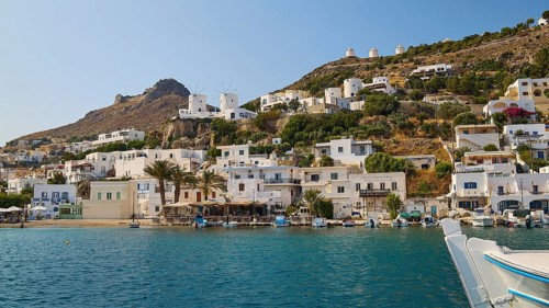 Coastal town with white houses on the hillside and a lively harbour in front of a blue sea,