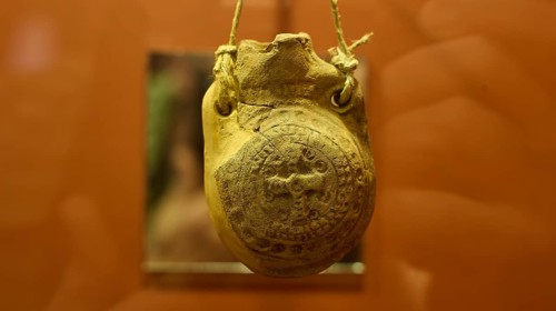 Ancient clay seal in a museum, hung with rope and detailed engravings, Archaeological Museum, Agia