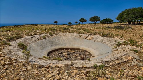 Dry terrain with a crater and scattered trees under a clear sky, Lost Place, Air Defence Position,