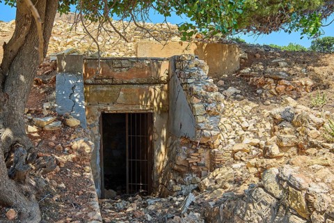 Closed ruin made of stone next to a tree in a sunny landscape, Lost Place, Air Defence Position,