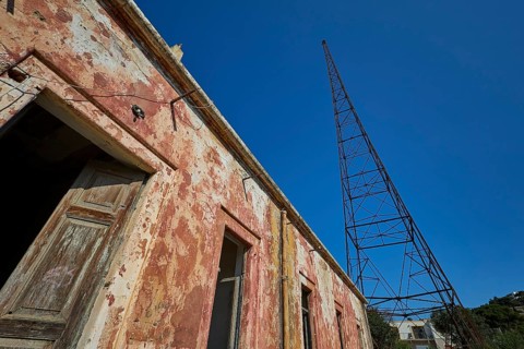 Lost Place, Old building with metal structure in the background, antenna mast, peeling plaster and