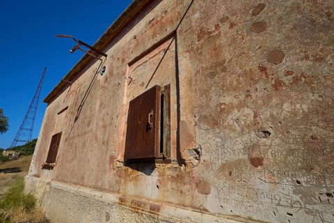 Lost Place, Old, peeling facade of a building with closed steel doors, Radio Station, WW2, Agios