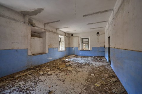 Lost Place, Abandoned room covered with rubble, blue wall plaster and damaged ceiling visible,