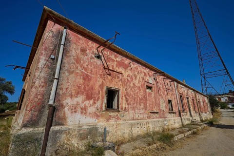 Lost Place, Red, peeling building with electric poles and cables under the open sky, Antenna mast,