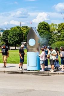 A queue of people in front of a drinking water fountain in the city centre of Vienna, Austria