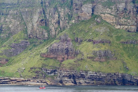 Steep cliffs and a tiny fishing boat convey a sense of grandeur, Hoy, Orkney Islands, Scotland,