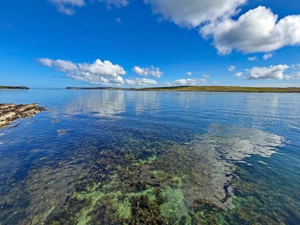 Clear sea with calm atmosphere, blue sky and clouds along the coastline, Hoy, Orkney Islands,