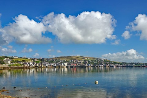 Coastal town with reflecting water, white sky and many clouds, Stromness, Mainland, Orkney Islands,