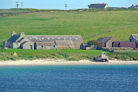 Rural scene with houses by the sea and green fields in the background, Lambholm, Orkney Islands,