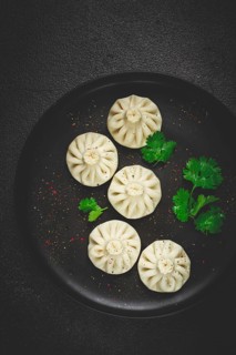 Khinkali, a traditional Georgian dish, with spices and herbs, top view, no people, on a black plate