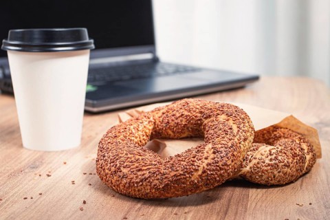 Simits with coffee on a wooden table, with a laptop, in a cozy working environment, snack,