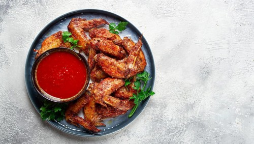 Fried in the oven, chicken wings, with spices, tomato sauce, on a plate, gray background, no